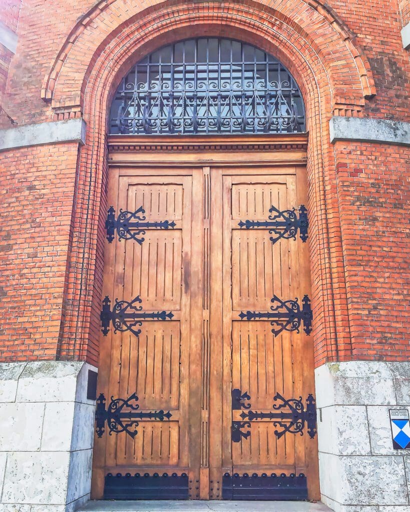 Photo close up of the massive wooden double doors with wrought iron hinges.
