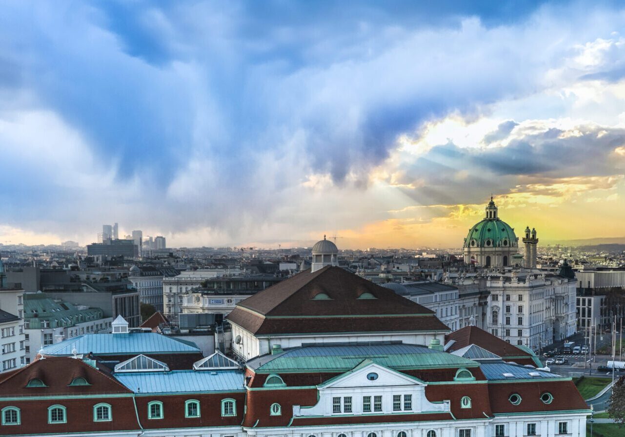Photo on cover of One Word Resolutions for the New Year Blog. Photo shows an 18th-century Habsburg domed Baroque church; The Rektoratskirche St. Karl Borromäus, commonly called the Karlskirche located on the south side of Karlsplatz in Vienna Austria. With a cloudy skyline at sunrise as orange and yellow rays poke through the clouds.